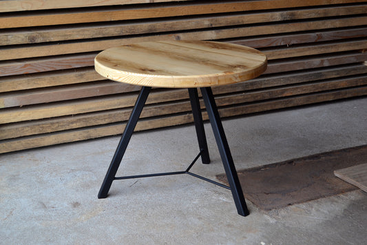 Wooden coffee table with black metal legs against a wooden wall.