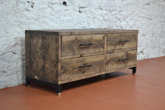 A brown chest of drawers made of reclaimed wood with four drawers, supported by steel legs, with a raw coat finish.