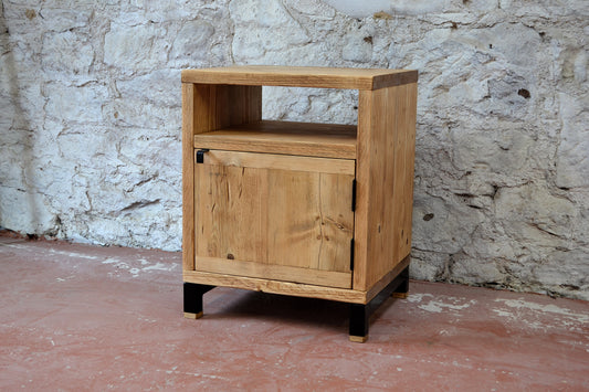 Wooden cabinet with a door against a stone wall.