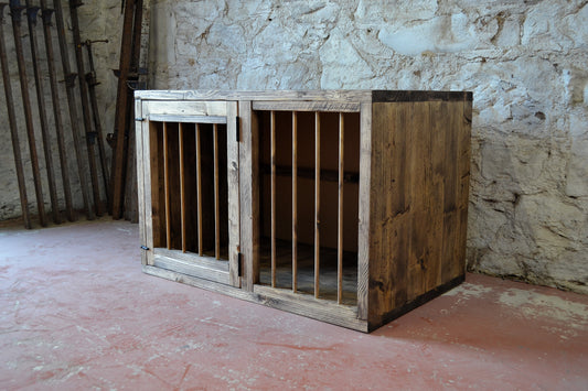 A wooden dog crate with metal spindles, constructed from reclaimed wood, designed for small to medium size dogs.
